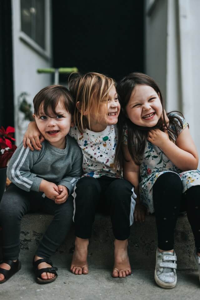 two girls and a boy sitting on the floor